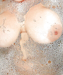 Voluptuous brunette enjoys a bubble bath